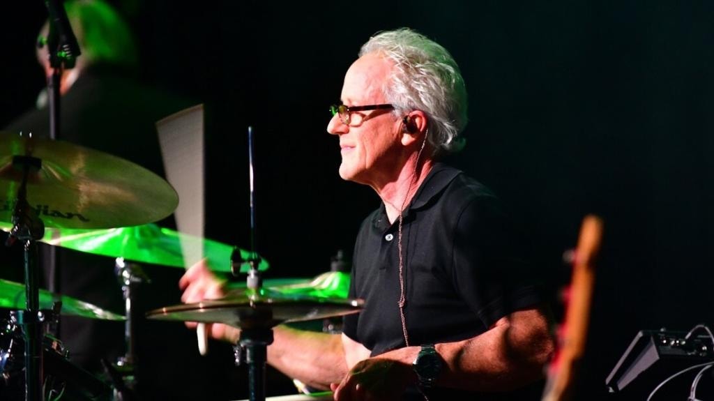 Drummer performing on stage with green lighting